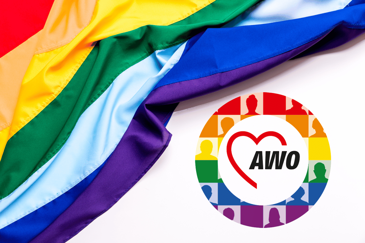 QueerPflege-LSBTIQ-Pflege Eine bunte LGBTQ+-Flagge ist neben einem runden Logo mit den Buchstaben „AWO“ und einem Herzsymbol drapiert, vor dem Hintergrund bunter menschlicher Silhouetten, die für queerfreundliche Pflege stehen.